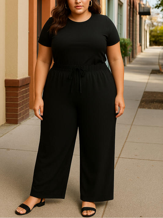 Woman wearing a black outfit standing on a sidewalk.