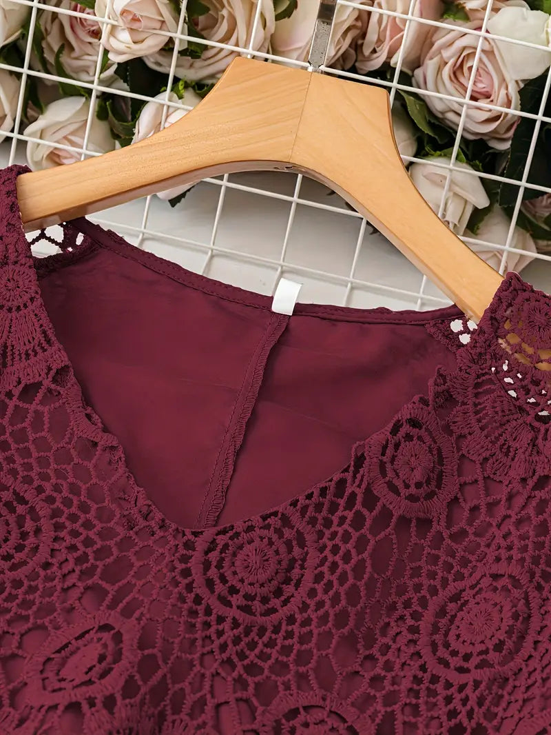 Maroon lace top on a wooden hanger with a floral background