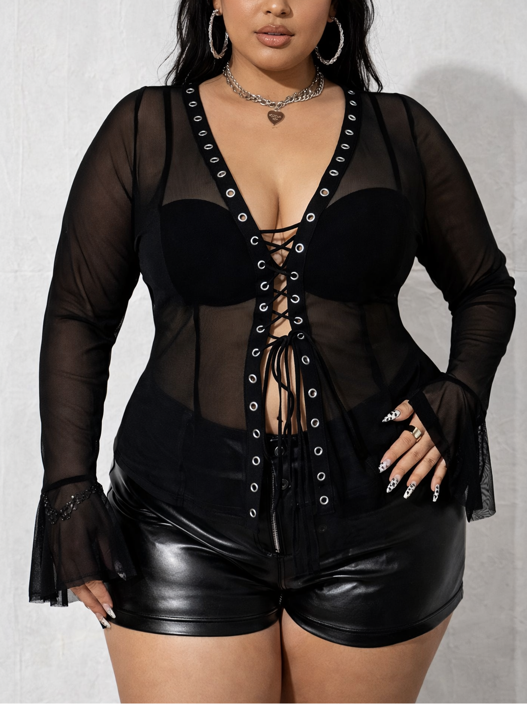 Woman wearing a black lace-up outfit with sheer panels on a white background
