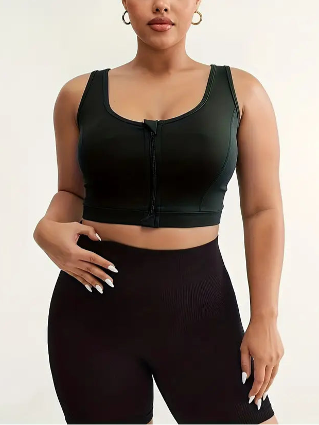 Woman wearing a black sports bra and high-waisted leggings on a plain background