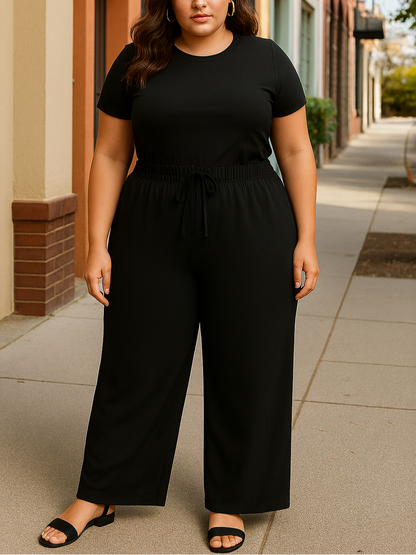 Woman wearing a black outfit standing on a sidewalk.