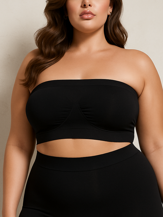 Woman wearing a black strapless top and high-waisted black shorts against a beige background