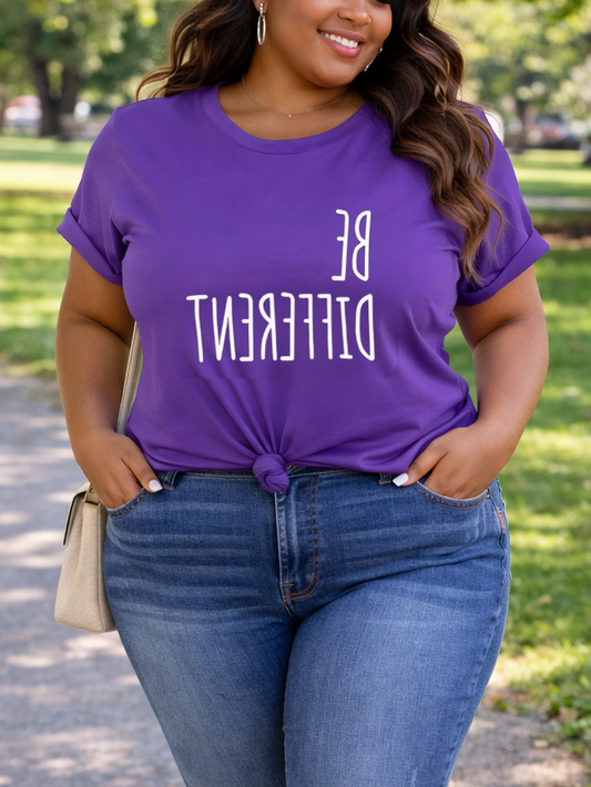 Person wearing a purple t-shirt with 'BE DIFFERENT' text and blue jeans, standing on a path in a park.