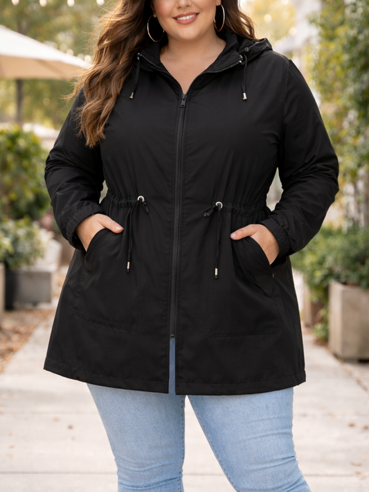 Woman wearing a black coat, light blue jeans, and brown boots standing outdoors.