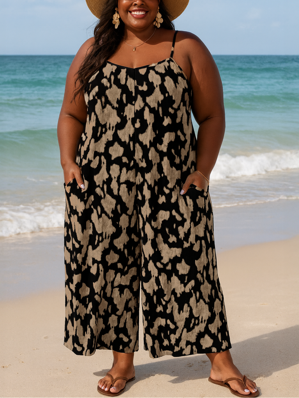 Woman in a leopard print dress and hat standing on a beach.