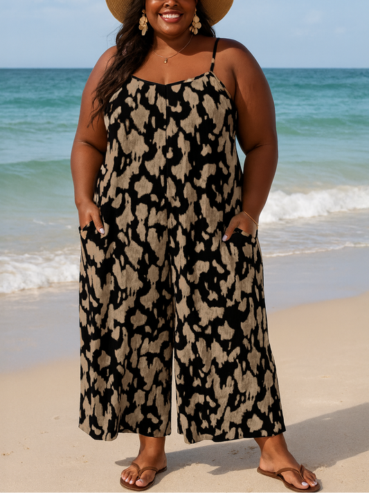 Woman in a leopard print dress and hat standing on a beach.
