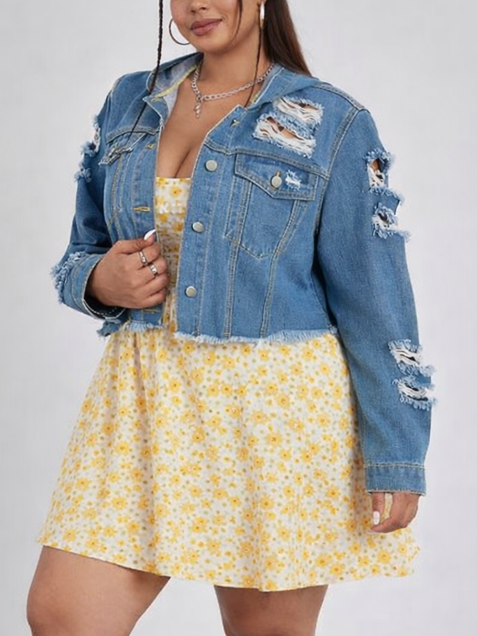 Woman wearing a yellow floral dress with a blue denim jacket on a gray background