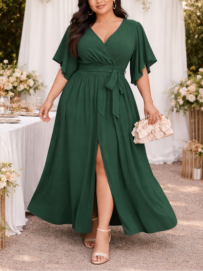 Woman in a green dress standing outdoors with floral decorations and a table in the background