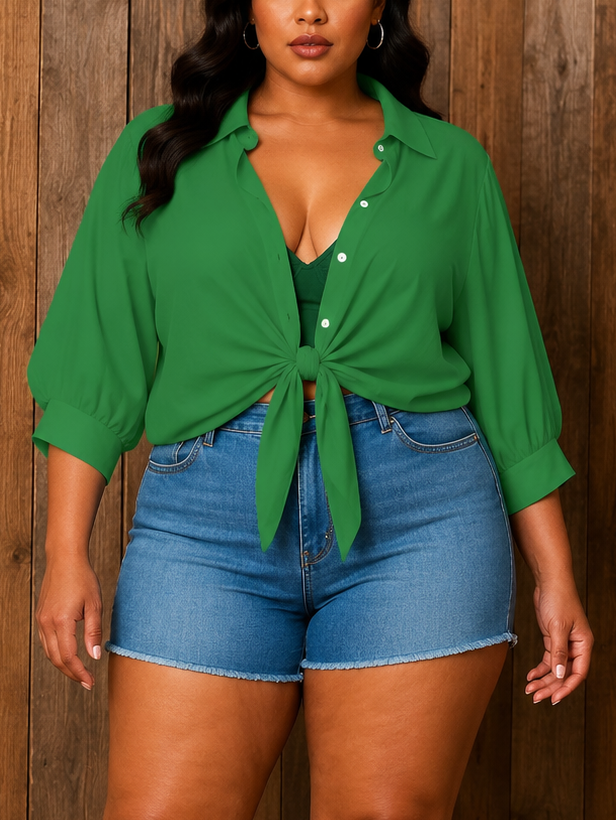 Woman wearing a green shirt and blue shorts against a wooden paneled wall.