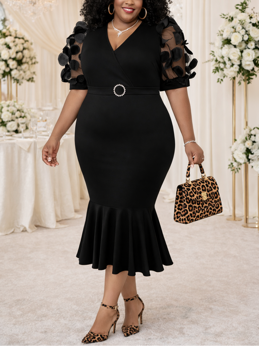 Woman in a black dress with floral sleeves holding a leopard print handbag in an elegant indoor setting.