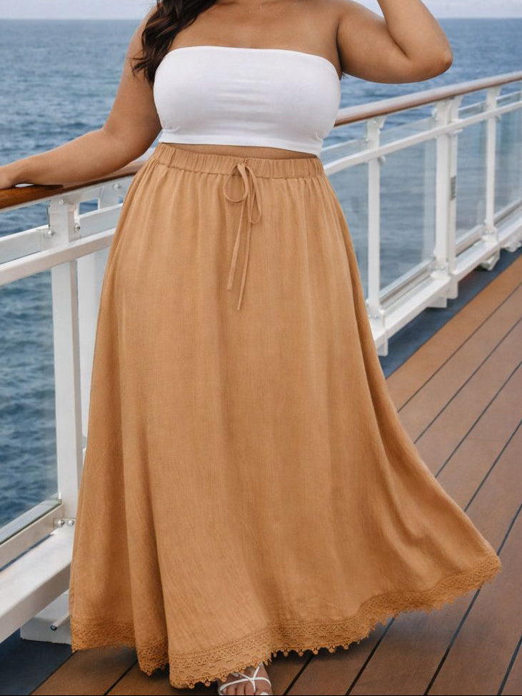 Woman in white top and tan skirt standing on a cruise ship deck with ocean view