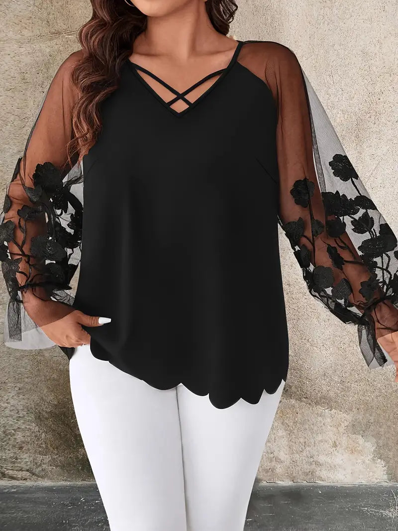Black top with sheer sleeves and floral embroidery worn by a plus size woman against a neutral background