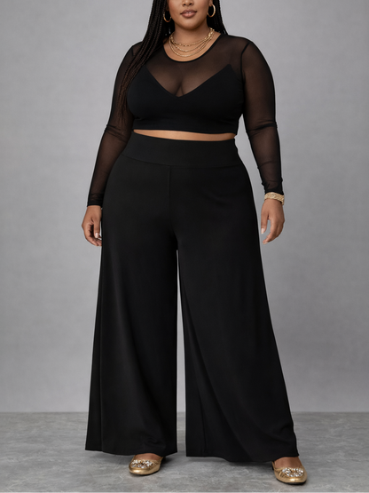 Woman wearing a black outfit with sheer sleeves against a gray background