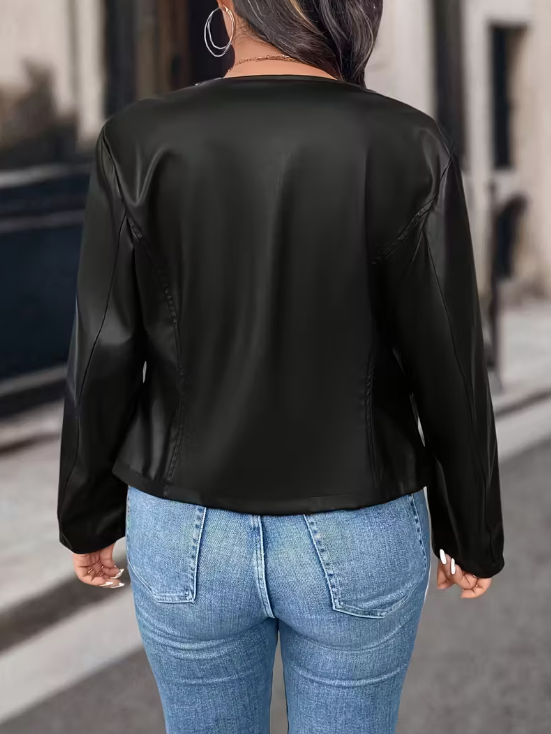 Person wearing a black leather jacket and blue jeans on a city street.