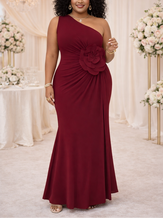 Woman in a burgundy one-shoulder dress with a floral detail in a decorated room.
