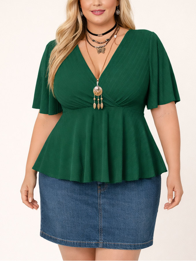Woman wearing a green peplum top and denim skirt on a white background