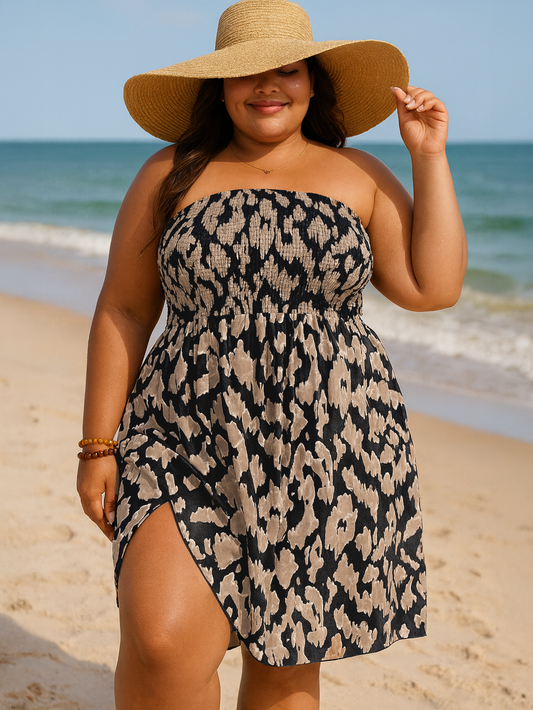 Woman in a strapless leopard print dress and wide-brimmed hat on a beach.