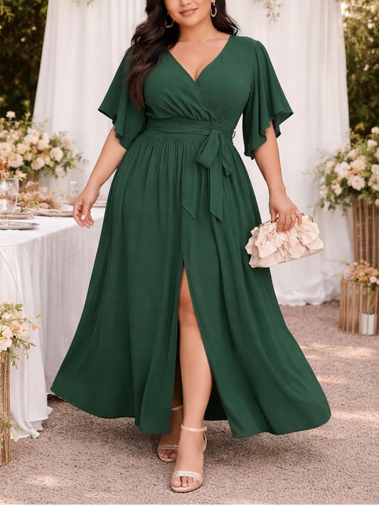 Woman in a green dress standing outdoors with floral decorations and a table in the background