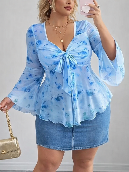 Woman wearing a blue floral top and denim skirt, holding a gold handbag.