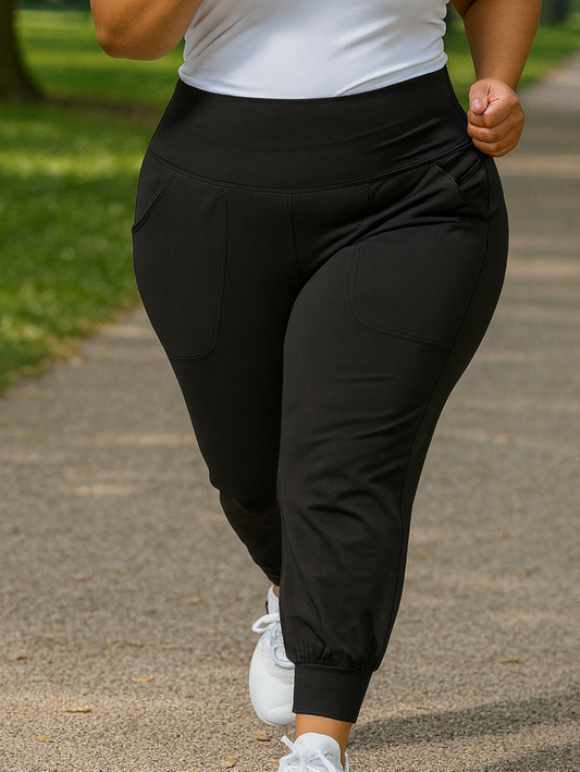 Person running on a path in a park wearing a white tank top and black pants.