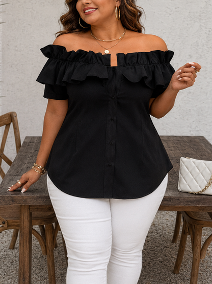 Woman wearing a black off-shoulder top and white pants standing in a casual setting.