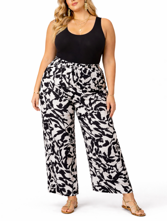 Woman wearing a black tank top and white patterned pants on a white background