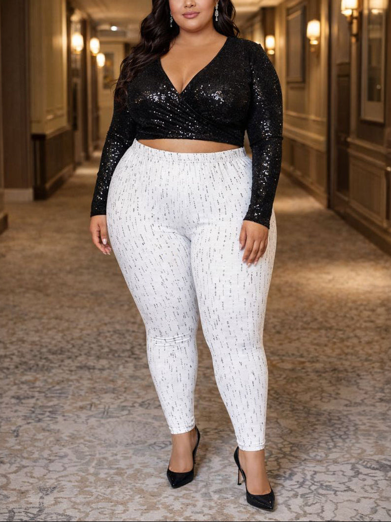 Woman wearing a black sequin top and white patterned pants in a hallway.