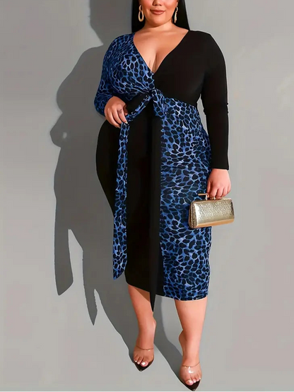 Woman wearing a black and blue leopard print dress holding a gold clutch against a gray background