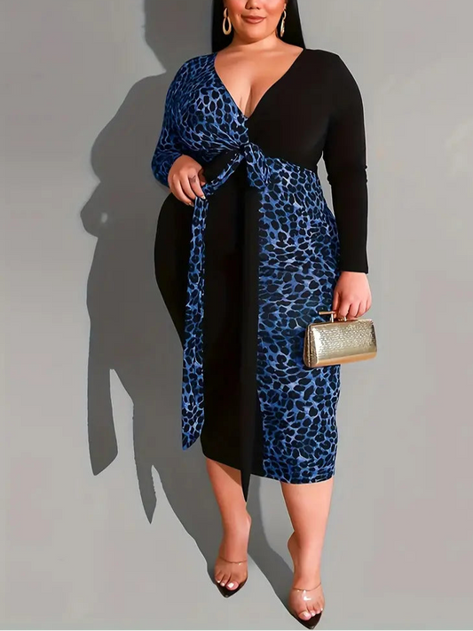Woman wearing a black and blue leopard print dress holding a gold clutch against a gray background