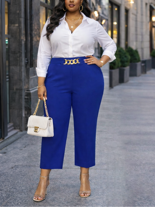 Woman in a white shirt and blue pants standing on a city street.