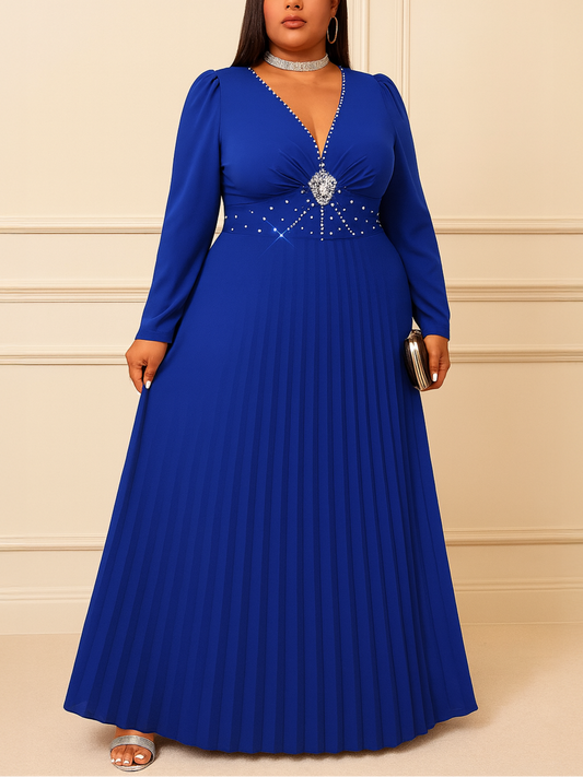 Woman wearing a blue evening gown with a beaded belt against a beige wall.