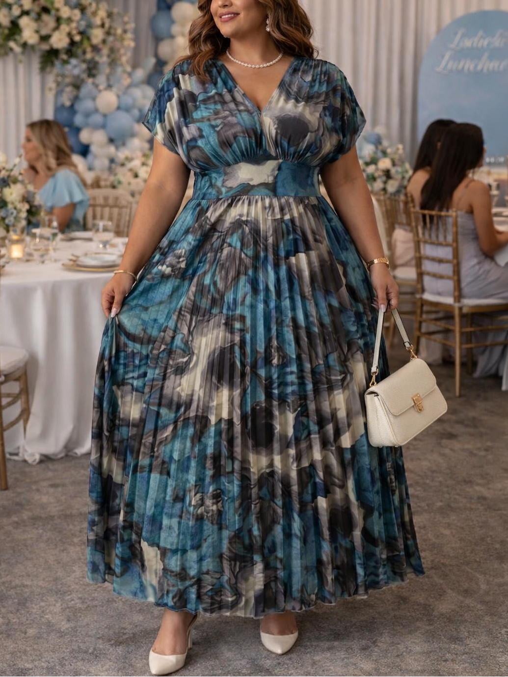 Woman in a blue patterned dress at a formal event with tables and decorations.