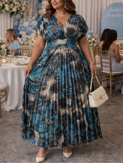 Woman in a blue patterned dress at a formal event with tables and decorations.