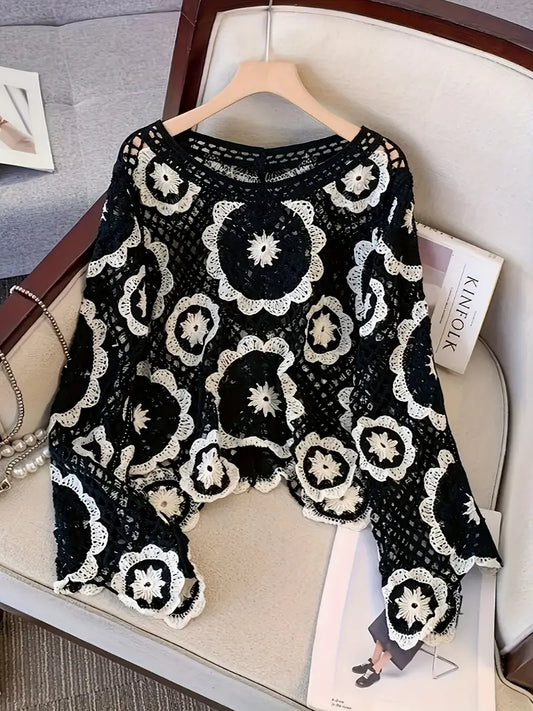 Black lace top with white floral patterns on a hanger against a neutral background