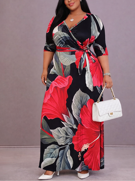 Woman wearing a colorful floral dress holding a white handbag against a gray background