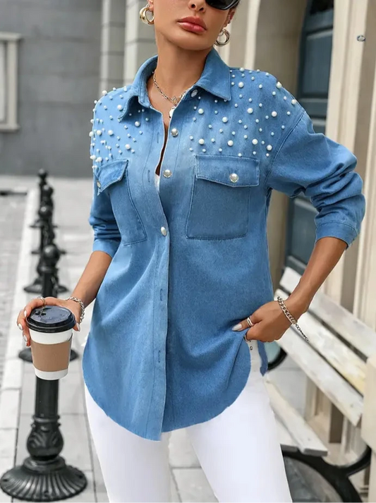 Woman wearing a blue studded shirt holding a coffee cup outdoors.